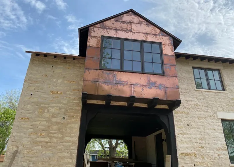 Copper metal panel facade on a stone building for Roof Repair in Belding